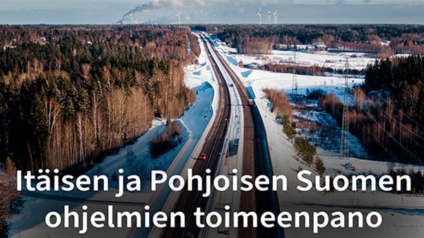 Ilmakuva, jossa tie halkoo talvista maisemaa, taustalla tuulimyllyjä